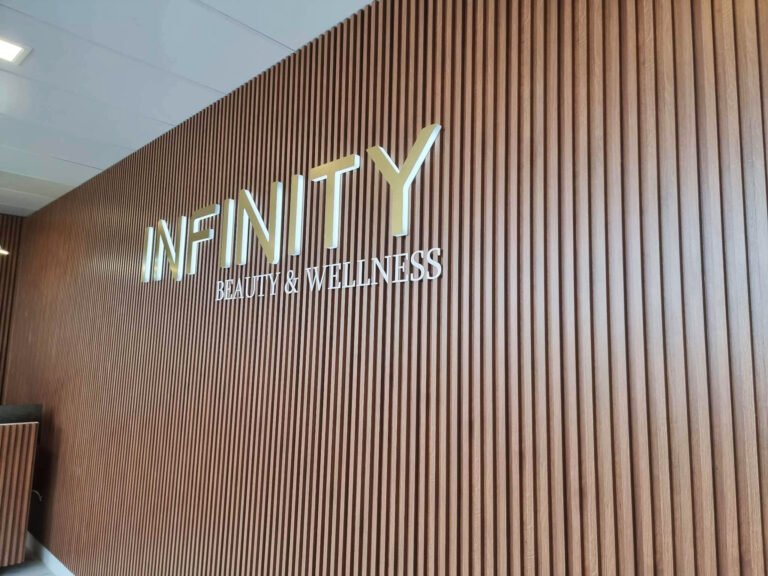 Infinity Beauty & Wellness metal lettering on a timber slat wall