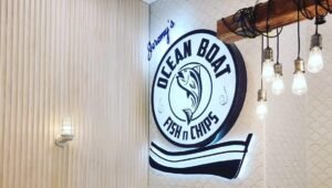 Illuminated Ocean Boat Fish n Chips logo sign on a timber slat wall