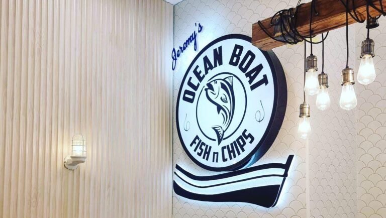 Illuminated Ocean Boat Fish n Chips logo sign on a timber slat wall
