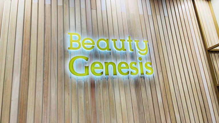 Beauty Genesis green illuminated lettering on a timber slat wall