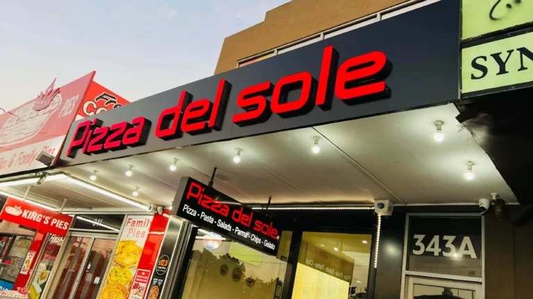 Illuminated red Pizza del Sole fascia sign above a shopfront