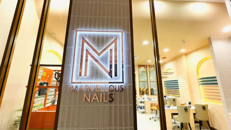 Illuminated M logo sign on a nail salon shopfront