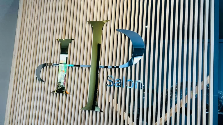 Gold and blue 3D logo sign mounted on a timber slat feature wall