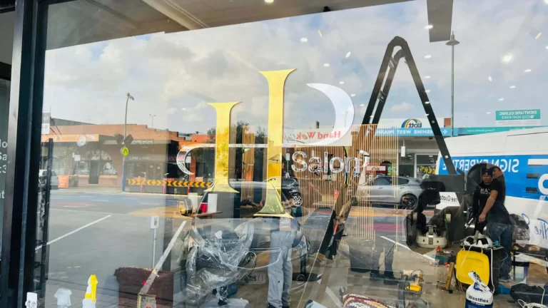 Gold and blue 3D logo sign viewed through a shopfront window