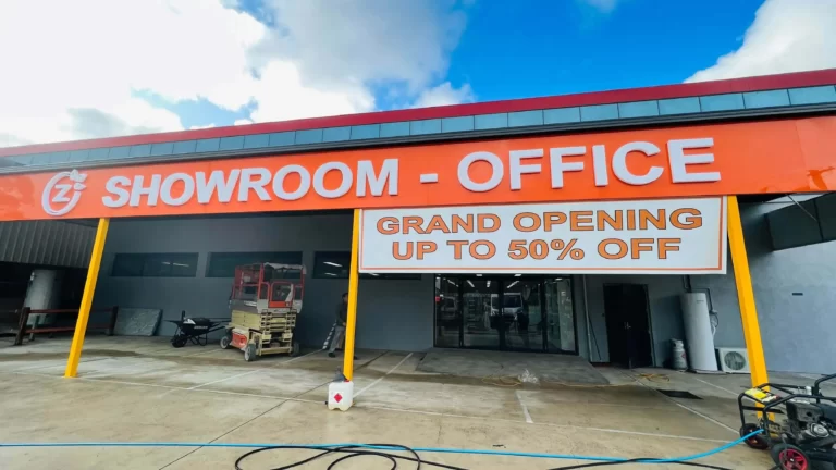 Orange showroom and office fascia sign with a grand opening banner