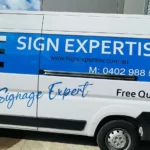 Side of a white van with Sign Expertise logo and phone number graphics