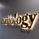 Nailology backlit 3D letter sign on a dark grey wall