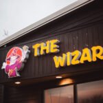 The Wizard illuminated 3D letter sign on a dark timber facade