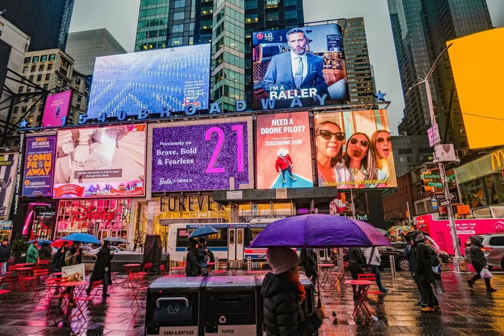Busy city street lit by large digital billboards at night