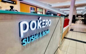 Illuminated Pokero Sushi & Bowl logo sign on a shop counter